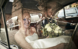 Bryllupsbillede af brudepar foran kirken i transpor bilen. Bryllups fotograf Fredericia.