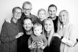 Familie fotograferet i studie på hvid baggrund. Klassisk familieportræt i sort hvid. Familiefotografering til private.