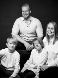 Familie fotograferet i studie på hvid baggrund. Klassisk familieportræt i sort hvid. Familiefotografering til private.